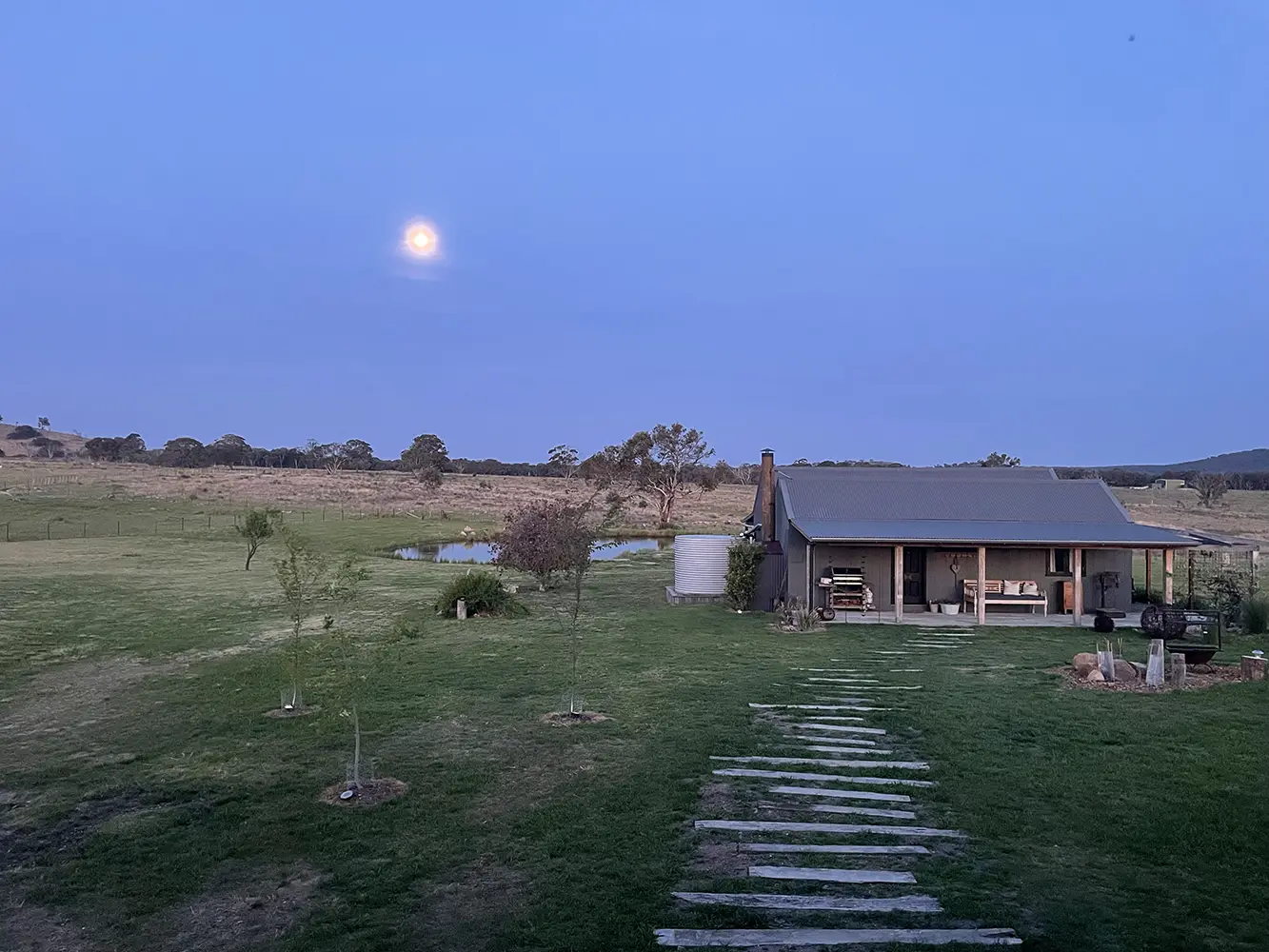 Farm stay at dusk with full moon and wooden pathway